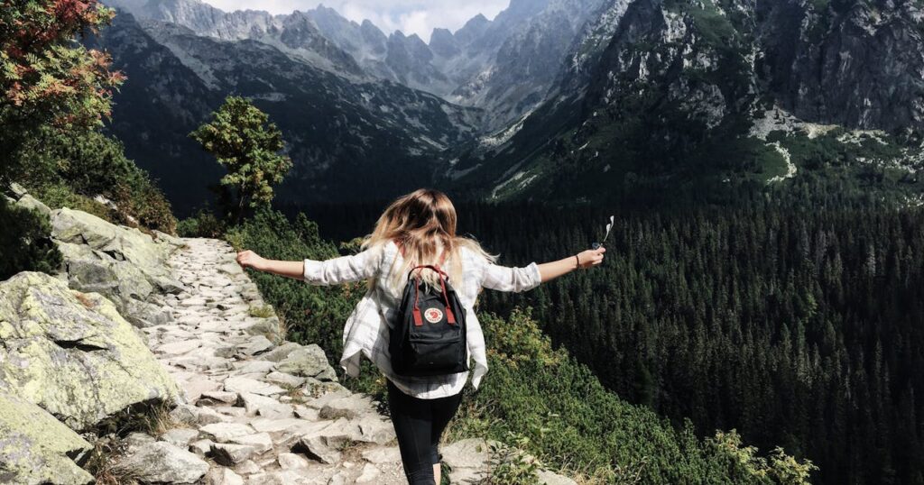 Woman hikes along rocky path in Vysoké Tatry, Slovakia. Embracing nature and freedom.